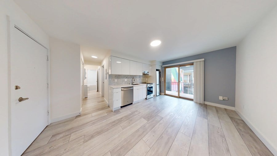A spacious room with wooden flooring and white walls.