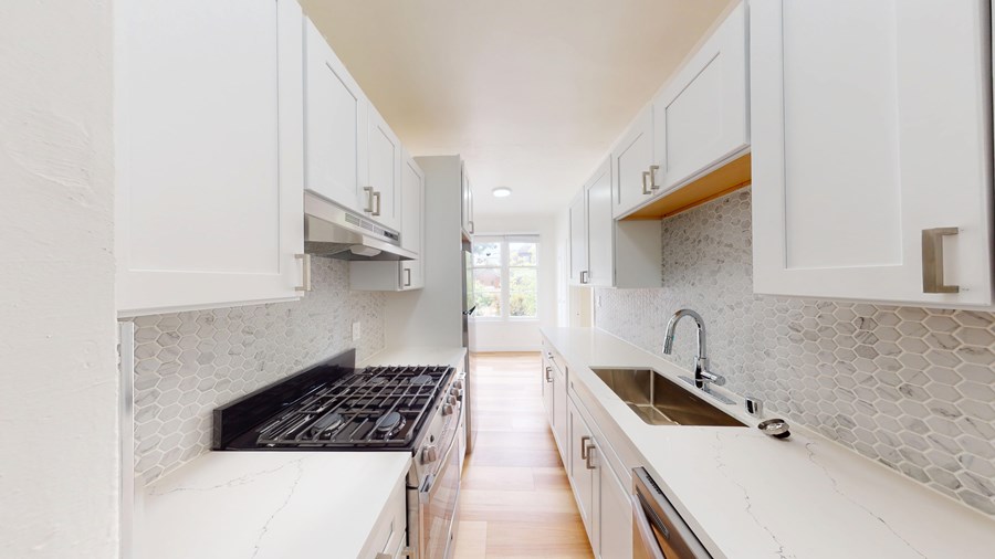 A modern kitchen with white cabinets and a tiled backsplash.
