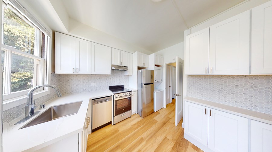 A kitchen with white cabinets and a wooden floor.