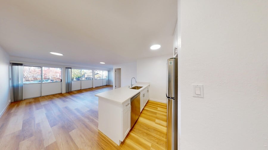 A kitchen with a white countertop and wooden floors.