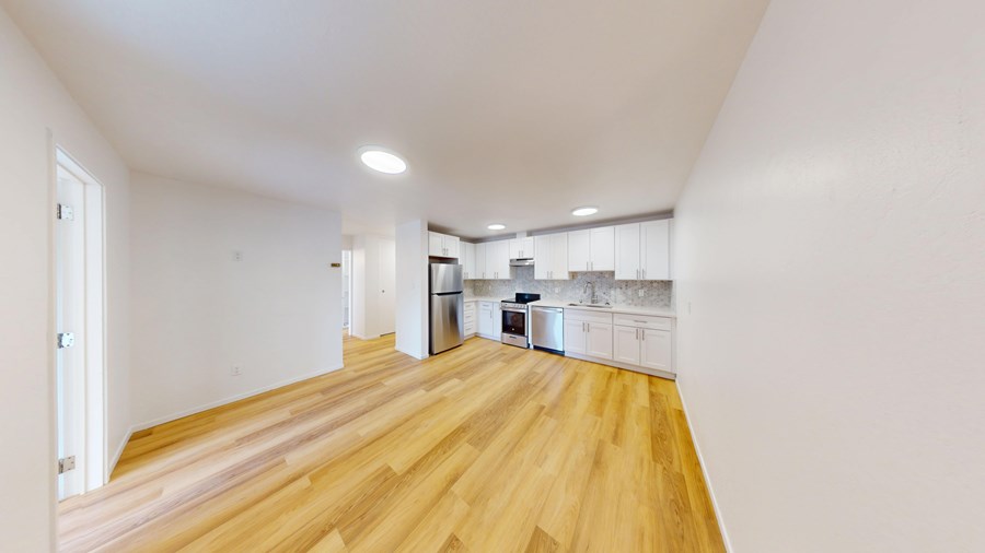 A kitchen with white cabinets and a wooden floor.