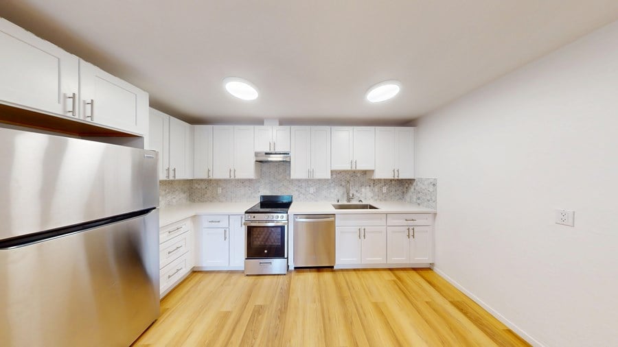 A modern kitchen with wooden floors and stainless steel appliances.