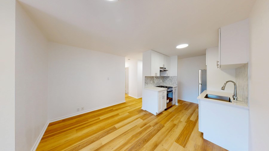 A kitchen with a sink and a refrigerator in a room with wooden floors.