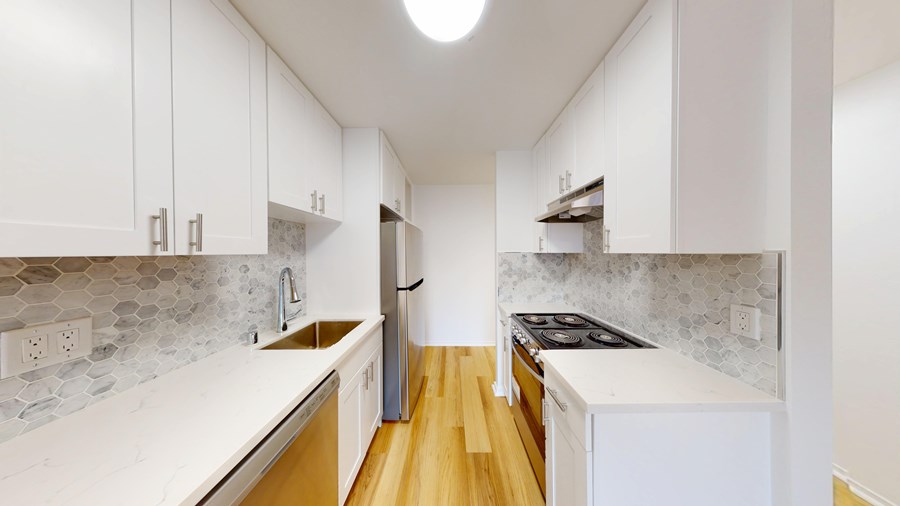A kitchen with white cabinets and a marble backsplash.