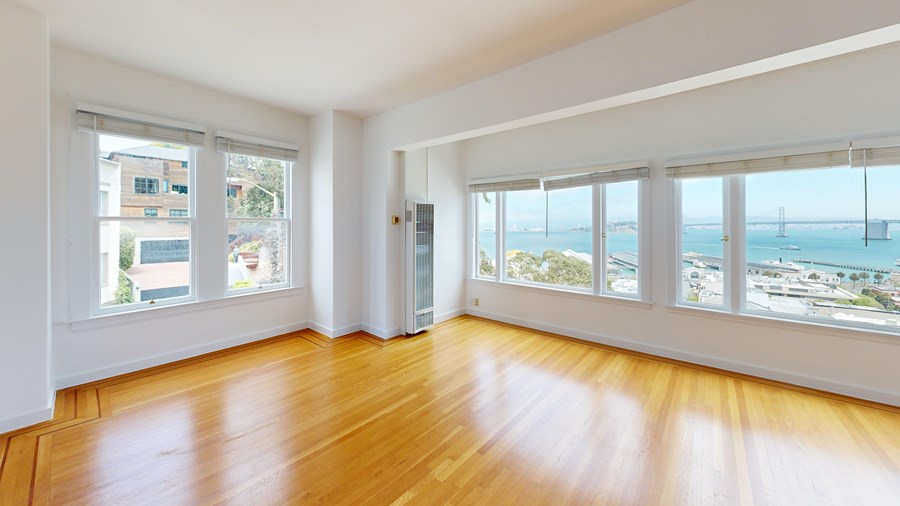 A room with wooden floors and large windows overlooking the sea.