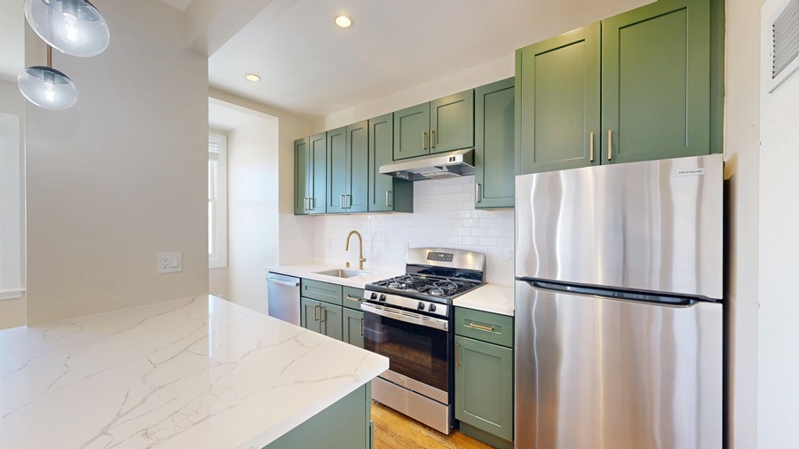A kitchen with green cabinets and a white fridge.