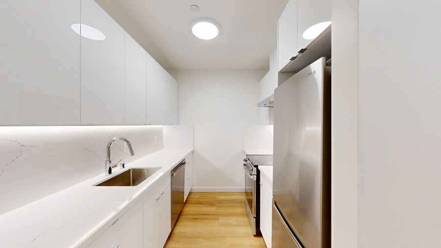 A modern kitchen with white cabinets and a stainless steel refrigerator.