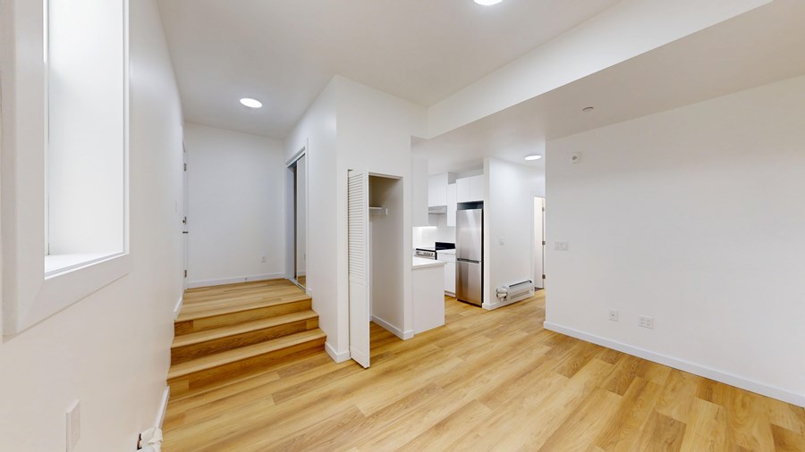 A spacious room with wooden floors and white walls.