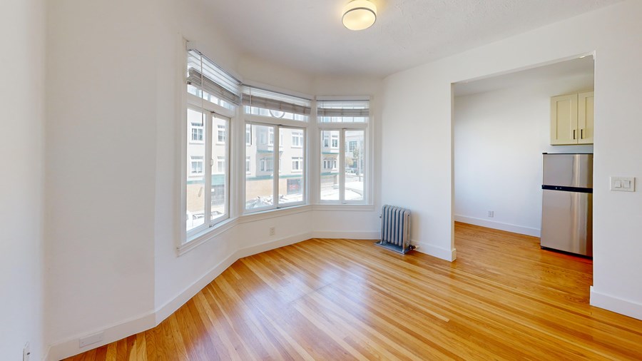 A room with wooden floors and a window overlooking a cityscape.