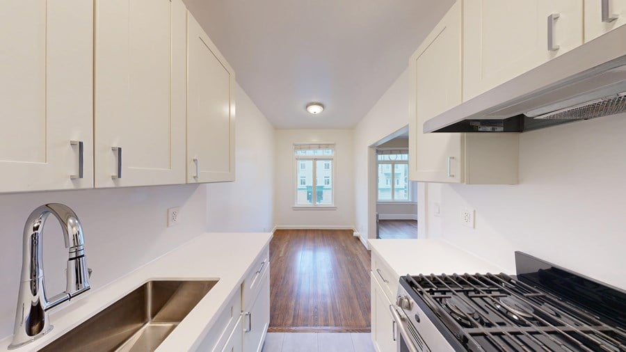 A kitchen with white cabinets and a black stove top oven.
