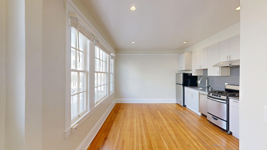 A kitchen with white cabinets and a wooden floor.