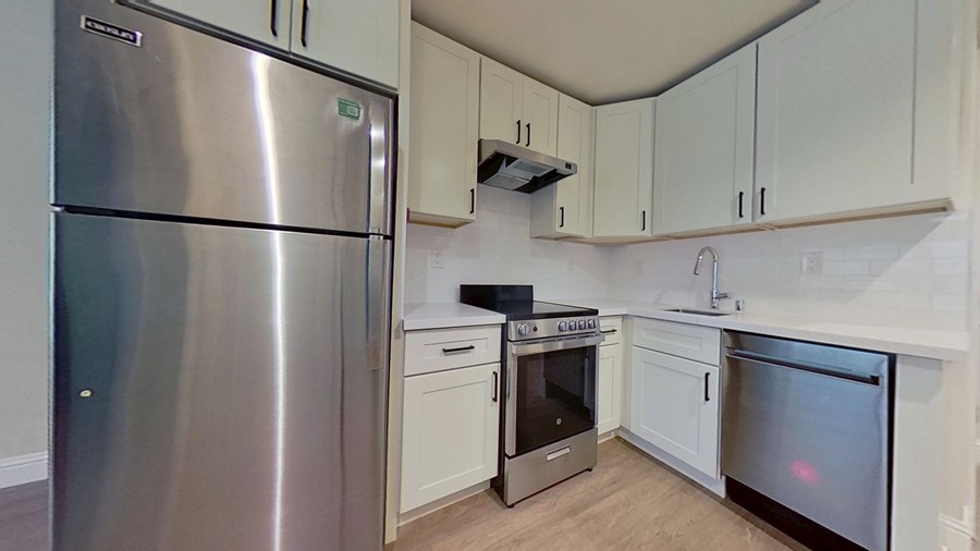 A kitchen with a stainless steel refrigerator and white cabinets.