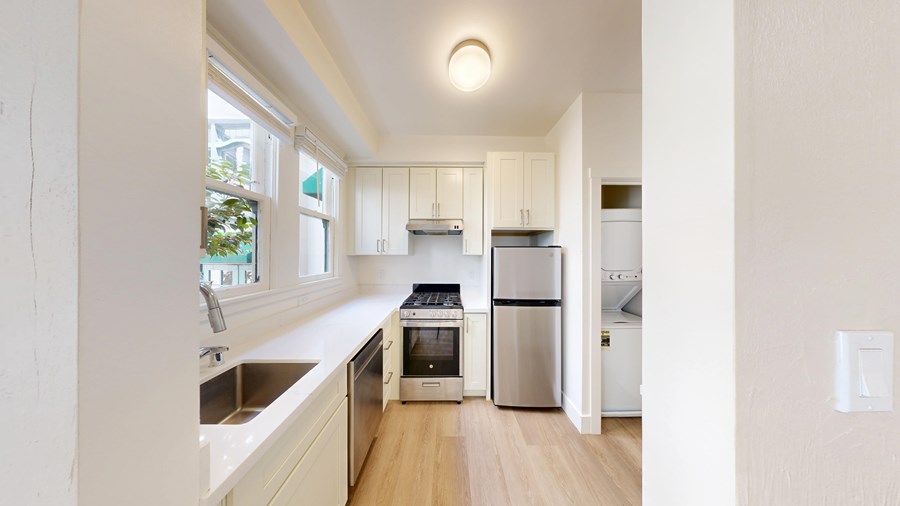 A kitchen with white cabinets and a wooden floor.
