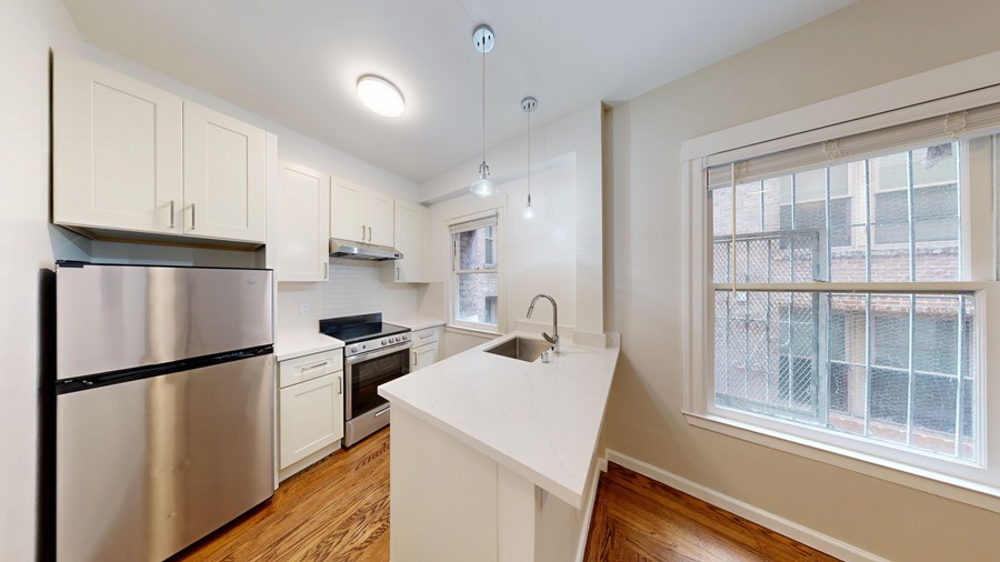 A kitchen with a stainless steel refrigerator and white countertops.