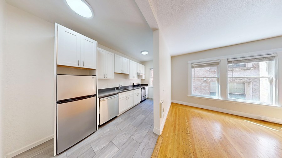 A kitchen with stainless steel appliances and wooden floors.