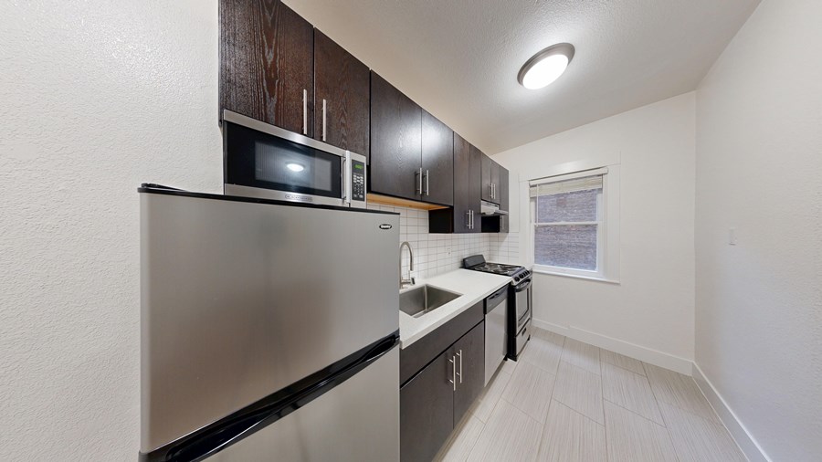 A kitchen with a stainless steel refrigerator, microwave, and oven.