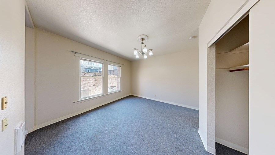 A room with a carpeted floor and a window overlooking a parking lot.