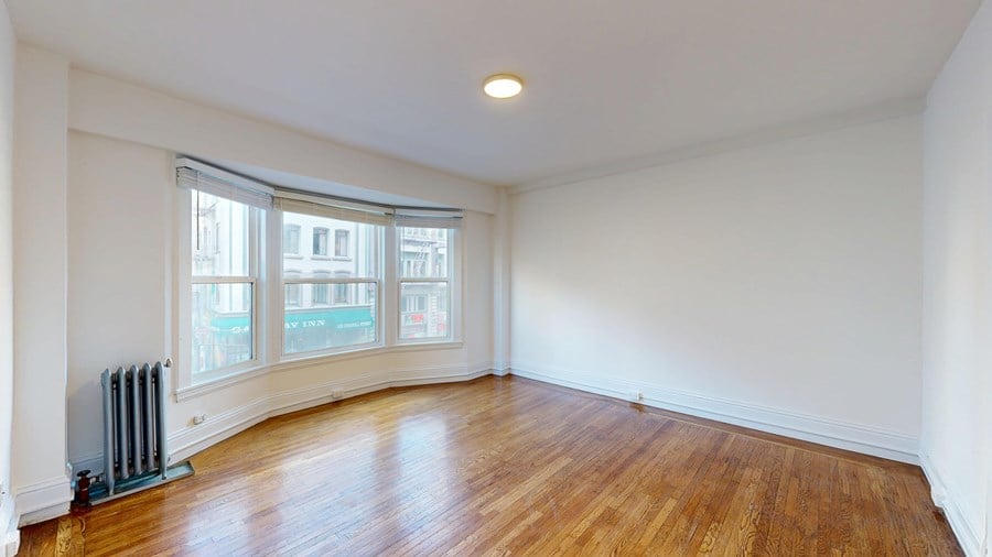 A room with wooden floors and a window with blinds.