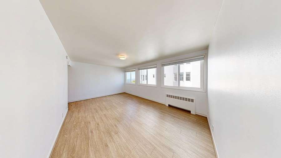 A room with wooden flooring and a window with blinds.