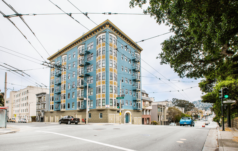 A blue and yellow building is situated on a street corner with cars parked on the side of the road.