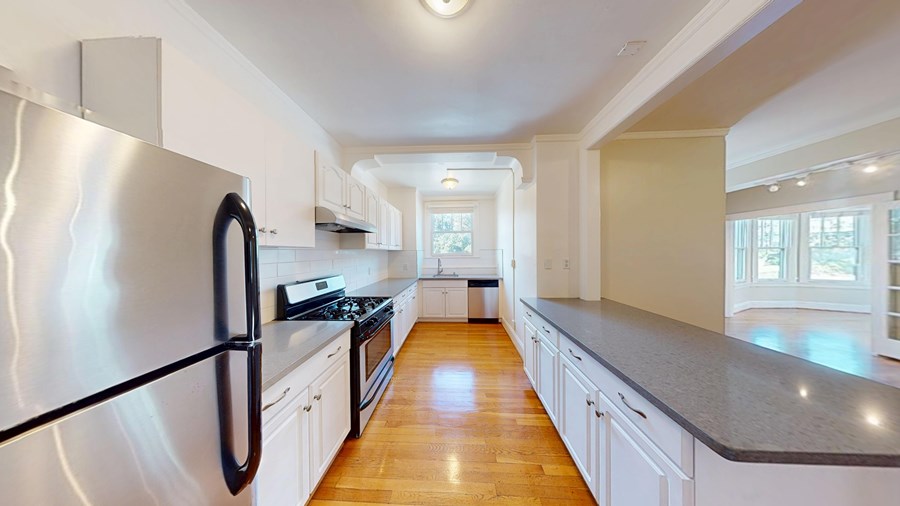 A modern kitchen with a black refrigerator and wooden floors.