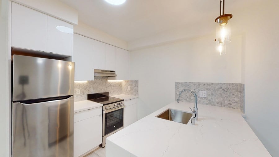 A kitchen with a stainless steel refrigerator and a marble countertop.
