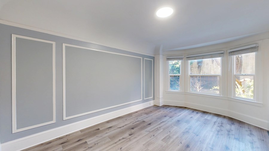 A room with a window and a wooden floor.