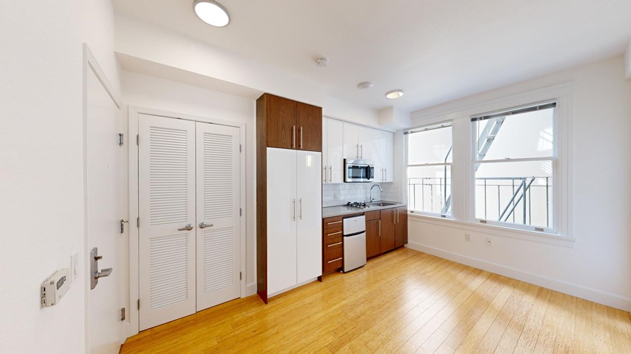 A kitchen with white cabinets and a wooden floor.