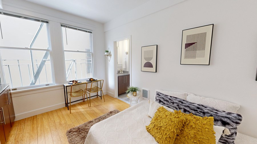 A bedroom with a bed, a chair, and two pictures on the wall.