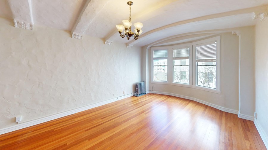 an empty living room with wood floors and a large window