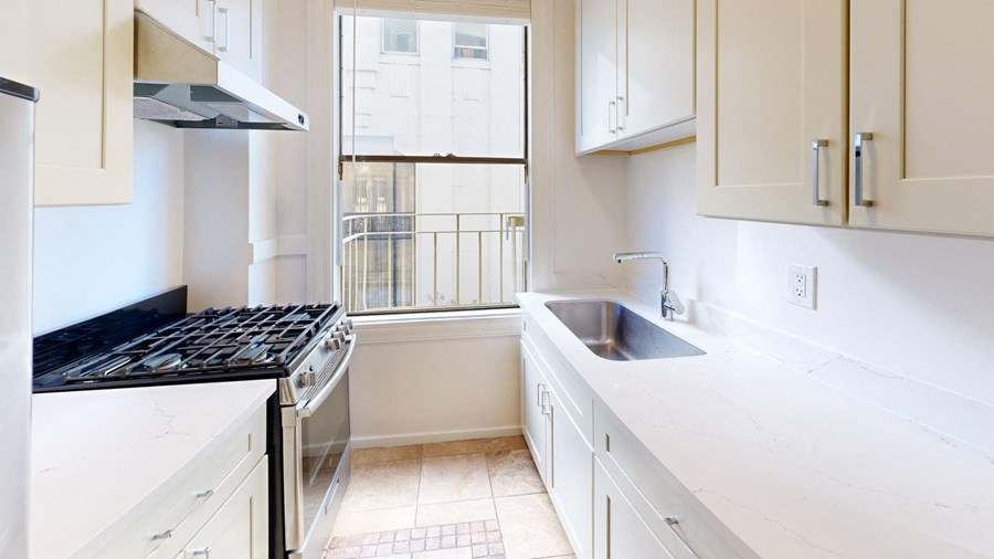 a kitchen with white cabinets and a sink and a window