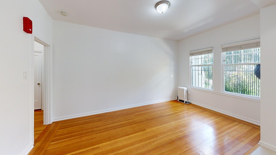 A room with a wooden floor and a window with blinds.