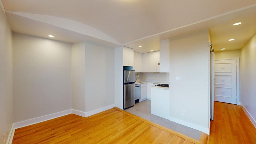 A kitchen with white cabinets and a wooden floor.