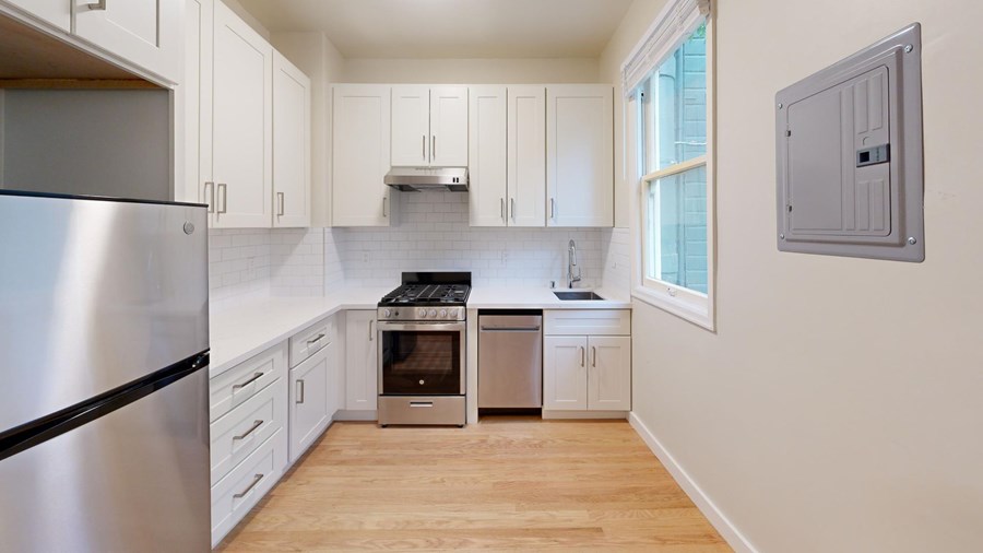 A kitchen with a stainless steel refrigerator and wooden floors.