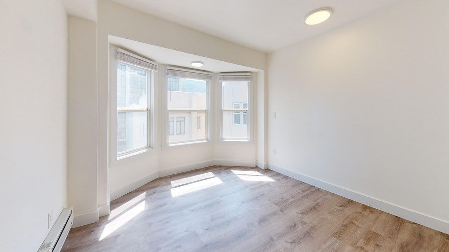 A room with a window and a wooden floor.