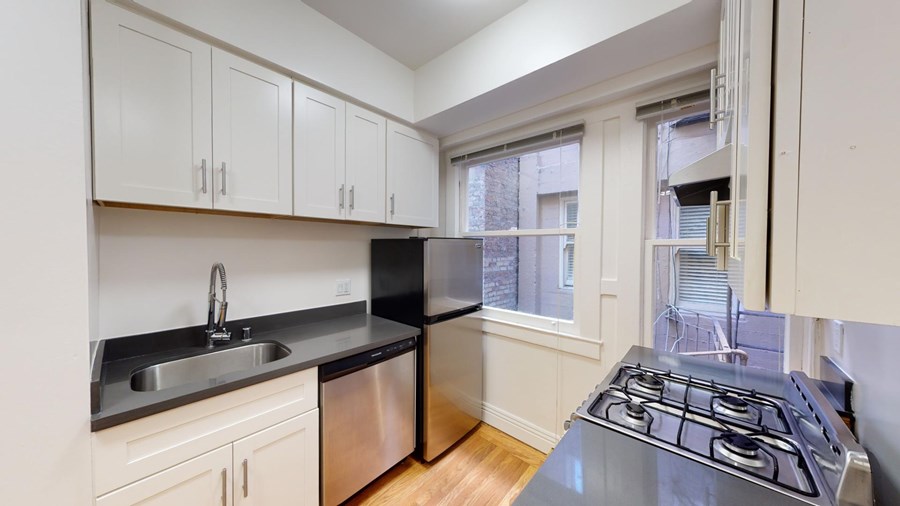 A kitchen with a stove, sink, and cabinets.