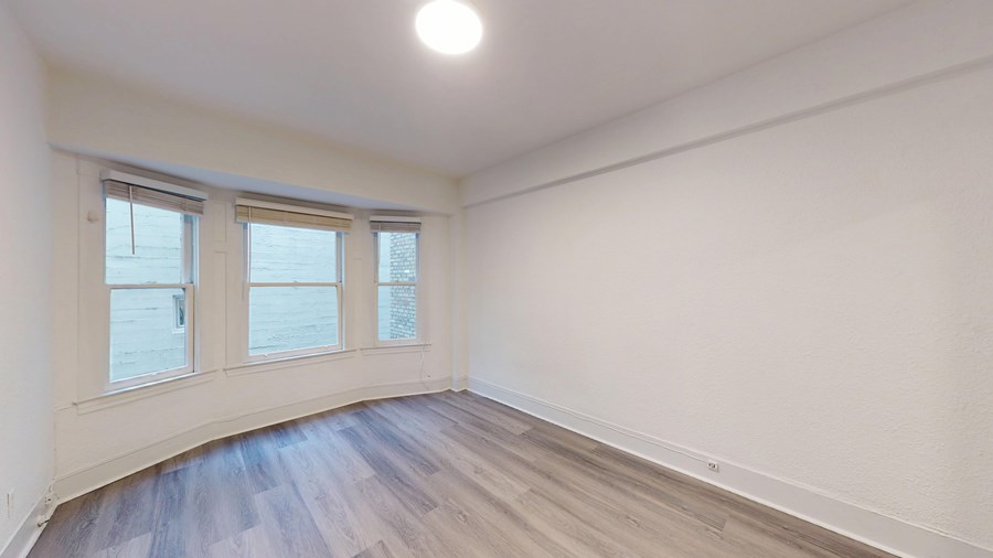 A room with a window and wooden flooring.