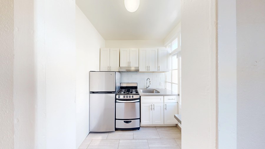 A kitchen with white cabinets and a stainless steel stove and refrigerator.