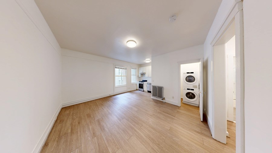 A spacious room with wooden flooring and white walls.