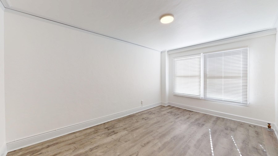 A room with a window and wooden flooring.