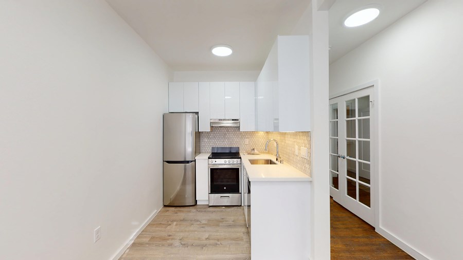 A kitchen with white cabinets and a stainless steel refrigerator.