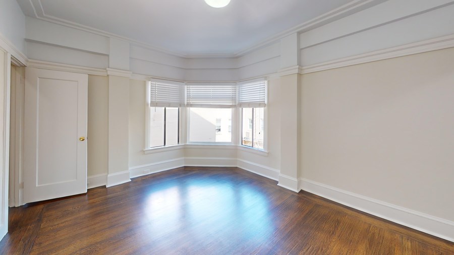 A large empty room with wooden floors and white walls.