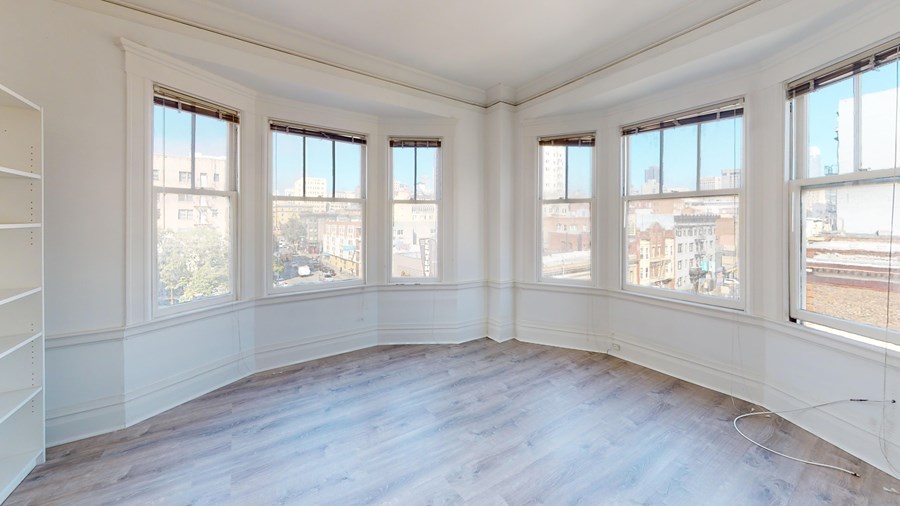 A large empty room with wooden floors and white walls.