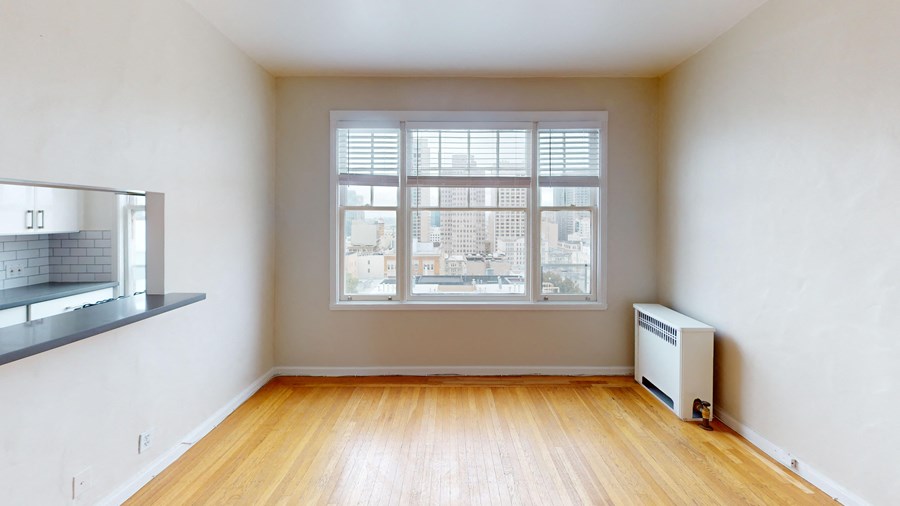 an empty living room with a window and wood floors