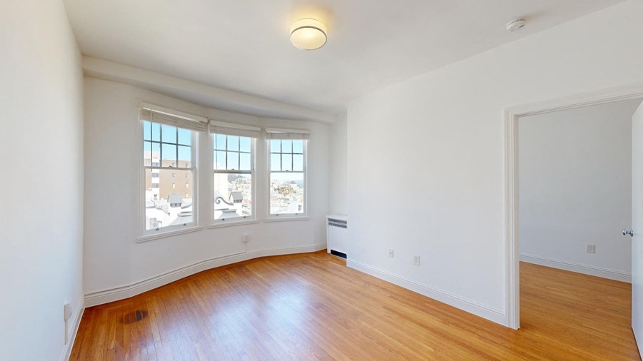 an empty living room with white walls and wood floors