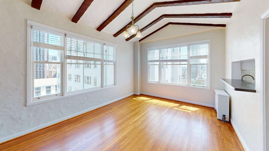 A room with wooden floors and white walls with windows.