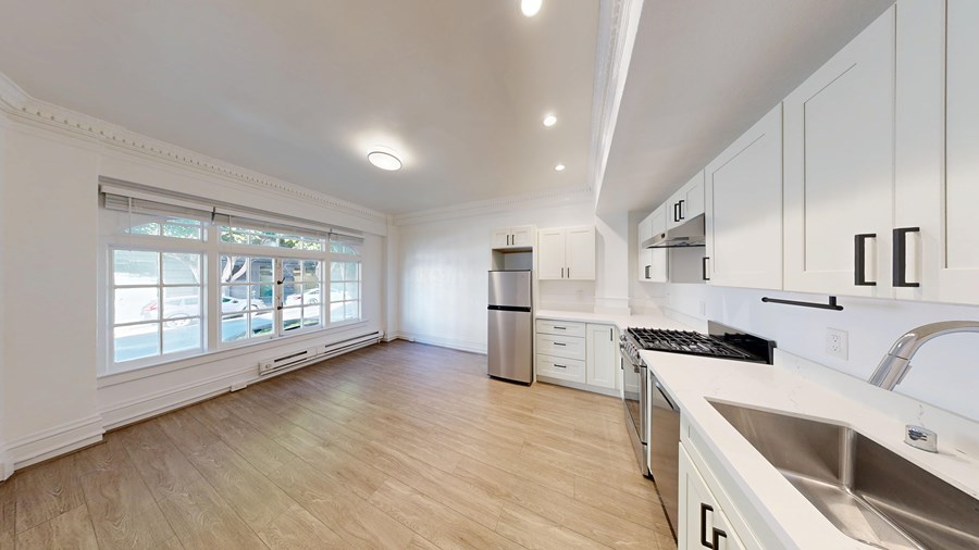 A kitchen with white cabinets and a stainless steel sink.