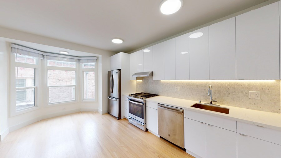A kitchen with white cabinets and a marble backsplash.