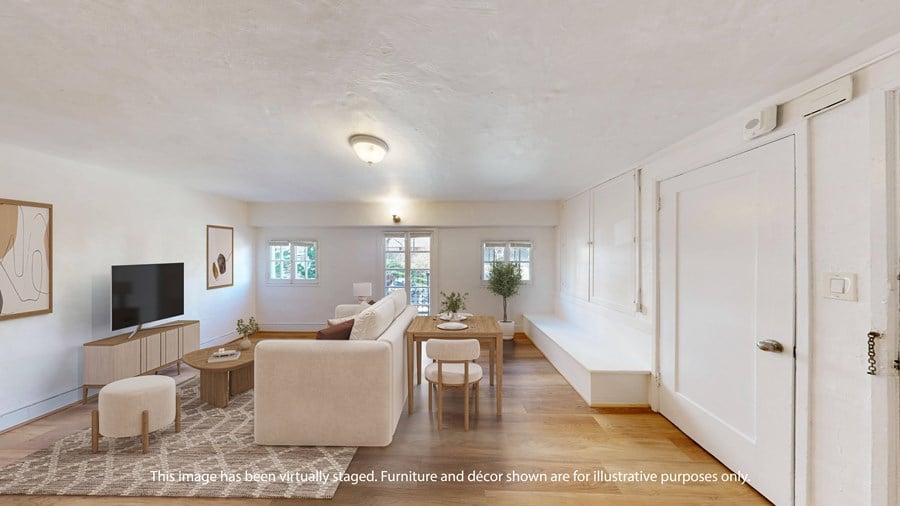 A living room with a white couch, a wooden table, and a television.
