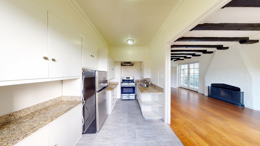 A kitchen with a refrigerator, oven, and sink.